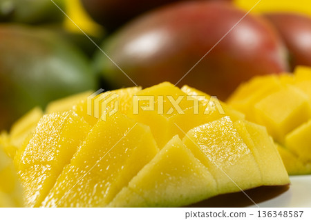 Juicy mango cubes with whole fruits on yellow background. Juicy mango cubes with whole fruits on yellow background. 136348587