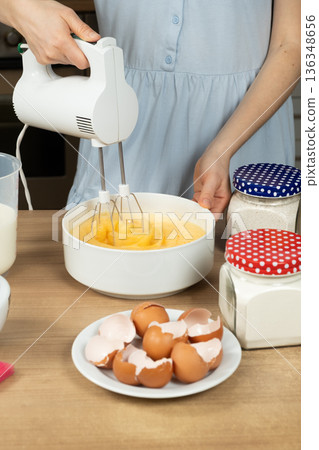Woman Using an Electric Hand Mixer to Whip Eggs for Waffle or Cake Batter. Woman Using an Electric Hand Mixer to Whip Eggs for Waffle or Cake Batter. 136348656