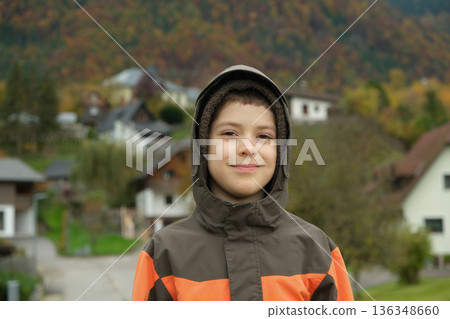 Portrait of happy 8 year old child in hooded jacket in autumn mountains. 136348660