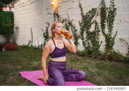 Mother enjoys refreshing drink after completing outdoor exercise routine 136348965