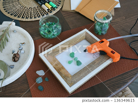 Sea glass in frame. Making art from natural materials. Glue gun and driftwood for picture. Hobbies and creativity. Reuse and nature, ecology.  136349615