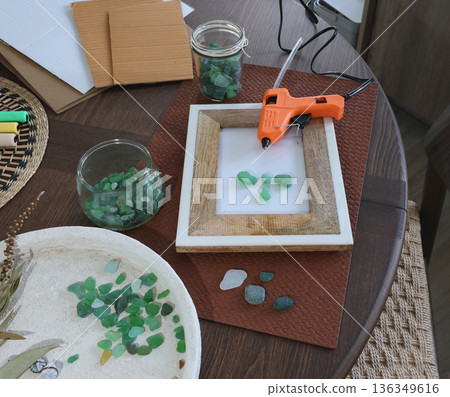 Sea glass in frame. Making art from natural materials. Glue gun and driftwood for picture. Hobbies and creativity. Reuse and nature, ecology.  136349616