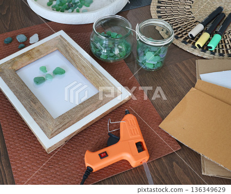 Sea glass in frame. Making art from natural materials. Glue gun and driftwood for picture. Hobbies and creativity. Reuse and nature, ecology.  136349629