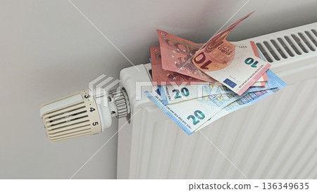 Radiator stacked with euro banknotes signals crisis in Europe winter, crisis hits household budgets, crisis mood fuels news visuals for energy projects, inflation reports 136349635