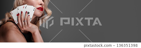 Blonde lady woman in black shiny dress and expensive diamond jewelry is winner money from Omaha Holdem. She is smiling, showing Aces cards to the camera. Ideal style for Poker, Casino, Gambling Blonde lady woman in black shiny dress and expensive diamond jewelry is winner money from Omaha Holdem. She is smiling, showing Aces cards to the camera. Ideal style for Poker, Casino, Gambling 136351398