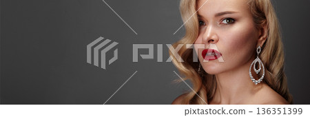 Closeup Caucasian Woman Wearing Diamond Earrings, Red Lipstick, Wavy Blonde Hair, Gray Studio Background, Luxury Jewelry Campaign Mood, Poised Expression, Dramatic Side Lighting, High Fashion Styling Closeup Caucasian Woman Wearing Diamond Earrings, Red Lipstick, Wavy Blonde Hair, Gray Studio Background, Luxury Jewelry Campaign Mood, Poised Expression, Dramatic Side Lighting, High Fashion Styling 136351399