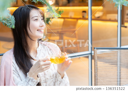 A young woman drinking tea on the terrace of a cafe A young woman drinking tea on the terrace of a cafe 136351522
