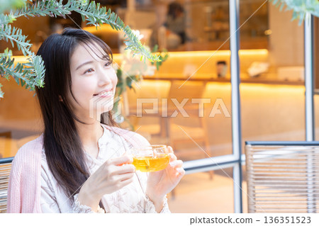 一位年輕女子在咖啡館的露臺上喝茶 136351523