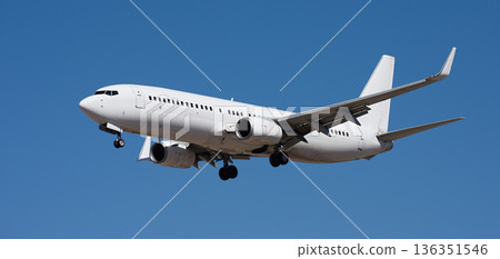 The plane lands. Airplane, passengers flying in the blue sky, preparing to land at the airport The plane lands. Airplane, passengers flying in the blue sky, preparing to land at the airport 136351546