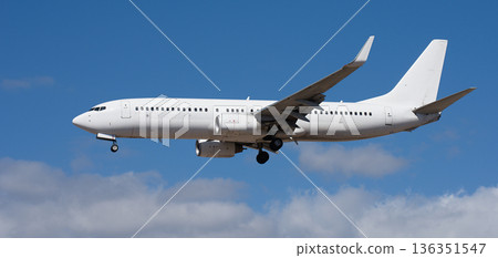 The plane lands. Airplane, passengers flying in the blue sky, preparing to land at the airport The plane lands. Airplane, passengers flying in the blue sky, preparing to land at the airport 136351547
