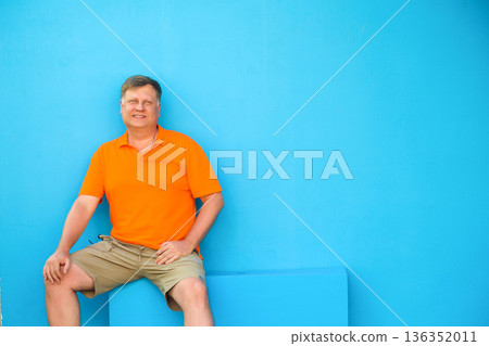 Portrait of an adult blond man against the blue wall of his house Portrait of an adult blond man against the blue wall of his house 136352011