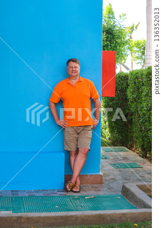 Portrait of an adult blond man against the blue wall of his house Portrait of an adult blond man against the blue wall of his house 136352013