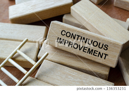 CONTINUOUS IMPROVEMENT text on wooden blocks on office desk representing ongoing process optimization and business efficiency. 136353231
