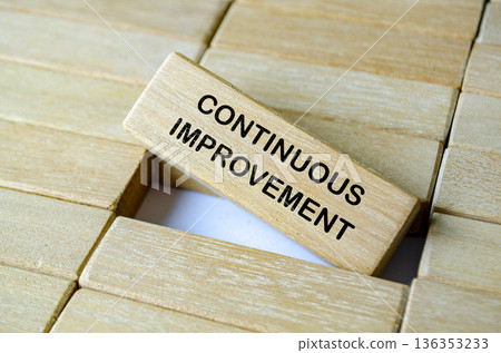 CONTINUOUS IMPROVEMENT text on wooden blocks with ladder representing step by step enhancement and organizational development. 136353233