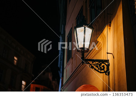 Ornate street lantern with decorative base on historic European building facade 136353473