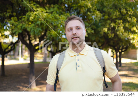 Man in Yellow Shirt Standing Outdoors in Green Park with Trees on Sunny Day Man in Yellow Shirt Standing Outdoors in Green Park with Trees on Sunny Day 136353544