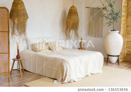 Boho bedroom interior with natural decor with cozy bed, wicker lamps and neutral tones 136353656