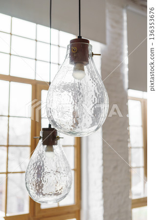 Decorative lamps, chandelier made of textured glass in loft living room on large window background Decorative lamps, chandelier made of textured glass in loft living room on large window background 136353676