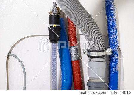 Assorted utility pipes, hoses, and plumbing connections for household appliances, demonstrating crucial water supply and effective drainage systems for home 136354010