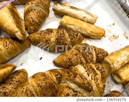 Freshly baked golden brown croissants with speckled toppings and crispy savory pastry rolls present a tempting delicious assortment of morning treats Freshly baked golden brown croissants with speckled toppings and crispy savory pastry rolls present a tempting delicious assortment of morning treats 136354278