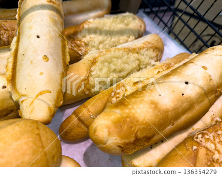 Freshly baked golden brown bread rolls with crispy cheese topping are displayed in a rustic bakery, offering a delicious and quick snack 136354279