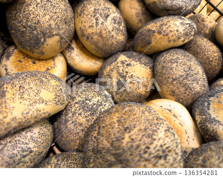 A generous pile of freshly baked golden brown poppy seed bread rolls, offering a wholesome and delicious texture, perfect for any morning meal or bakery offering 136354281