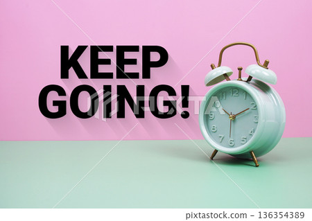 Black alarm clock on a pastel green and pink background with the text "Keep Going" Black alarm clock on a pastel green and pink background with the text "Keep Going" 136354389