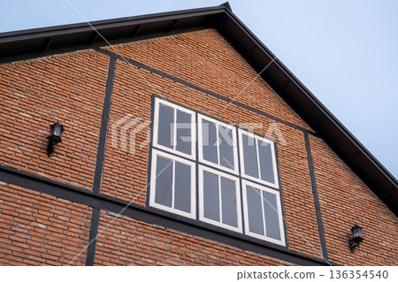 A modern brick building, with window and wall lamps. with blue sky on the background A modern brick building, with window and wall lamps. with blue sky on the background 136354540