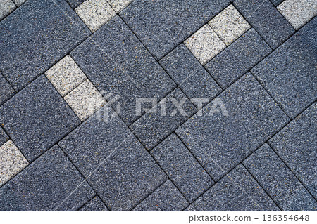 Dark gray paving tiles with speckled gravel texture and diagonal layout, accented by light tiles. Concept of paving tiles, textured surfaces, modern design background 136354648