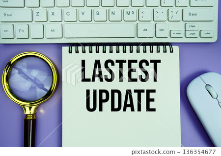 Notepad with the text "Last Update" with white keyboard, wireless mouse and magnifying glass on purple background 136354677
