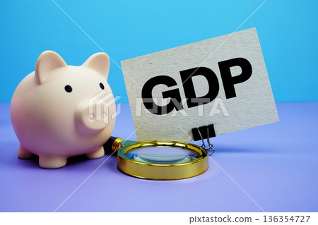 GDP text with piggy bank and magnifying glass on blue and purple background GDP text with piggy bank and magnifying glass on blue and purple background 136354727