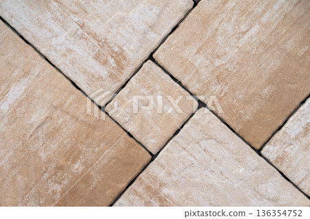 Square stone tiles laid diagonally forming repeating pavement pattern with visible joints, surface wear. Natural background of paving stone surface, landscape design, construction materials backdrop 136354752