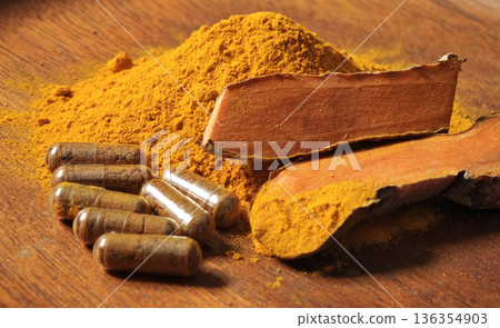 Turmeric powder, turmeric rhizomes, and turmeric capsules in a bowl. Turmeric powder, turmeric rhizomes, and turmeric capsules in a bowl. 136354903