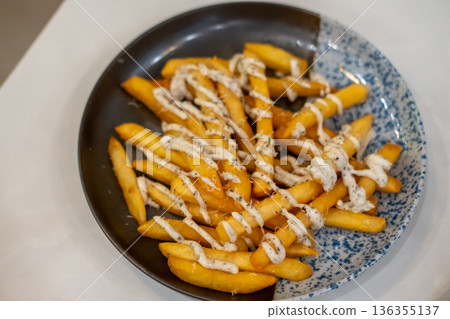 Close up of French Fries with cheese and black truffle mayo sauce on plate Close up of French Fries with cheese and black truffle mayo sauce on plate 136355137