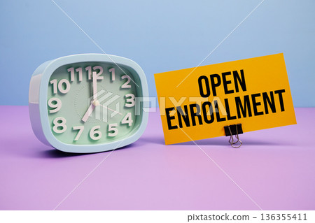 Open Enrollment text and alarm clock on blue and purple background 136355411