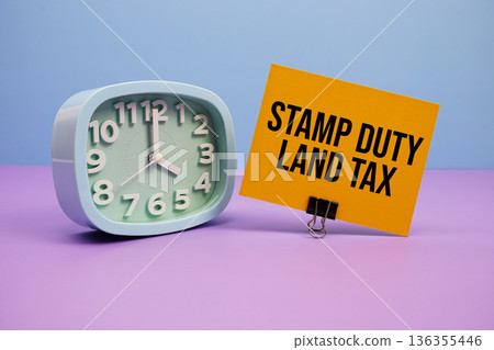 stamp Duty Land Tax text and alarm clock on blue and purple background 136355446