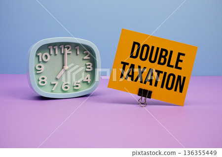 Double Taxation text and alarm clock on blue and purple background Double Taxation text and alarm clock on blue and purple background 136355449