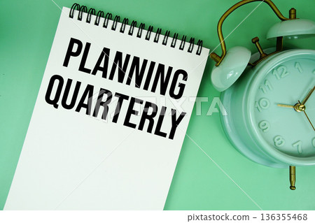 Planning Quarterly text with alarm clock flat lay on green background 136355468