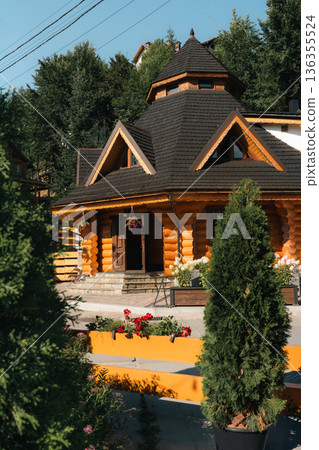 Traditional wooden log house with flowers and open door in mountain village 136355524