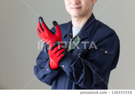 一位身著工作服的中年男性商務人士正在戴手套 136355559