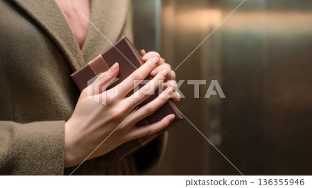 A man in an elegant coat holds a chocolate. 136355946