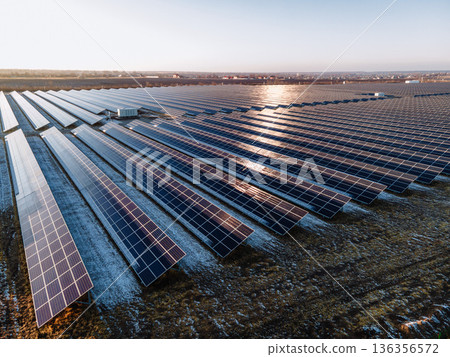 Large Scale Solar Power Plant with Rows of Photovoltaic Panels in Open Field During Cold Season Captured from Aerial Drone Perspective 136356572