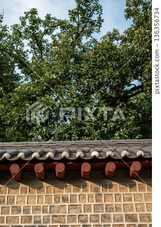 Traditional Korean tiled roof and stone wall under green tree canopy Traditional Korean tiled roof and stone wall under green tree canopy 136356734