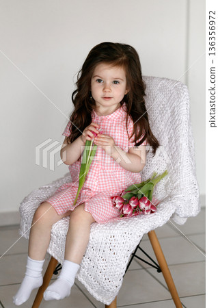 Little girl with pink tulips indoors 136356972
