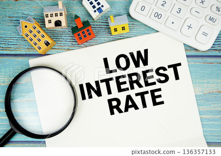 Notepad with "Low Interest Rate" with Calculator, magnifying glass and house model on wooden background Notepad with "Low Interest Rate" with Calculator, magnifying glass and house model on wooden background 136357133
