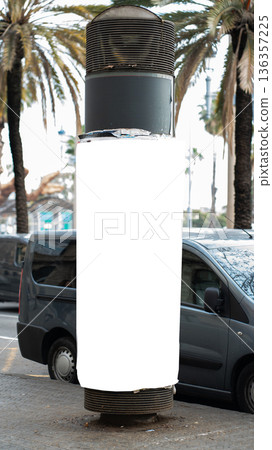 Blank advertising column mockup standing on a city street pavement with parked minivans and palm trees in the background, creating a perfect space for outdoor media marketing Blank advertising column mockup standing on a city street pavement with parked minivans and palm trees in the background, creating a perfect space for outdoor media marketing 136357225