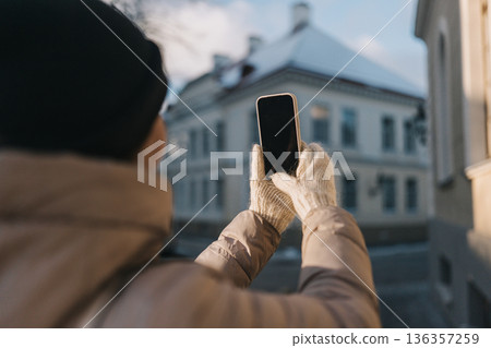 Person takes picture of building with phone in winter setting in a town Person takes picture of building with phone in winter setting in a town 136357259