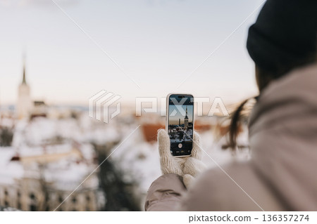 Person holding phone and taking picture of city in winter during sunny day Person holding phone and taking picture of city in winter during sunny day 136357274