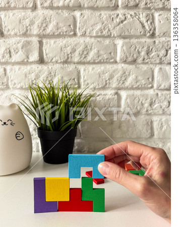 A woman's hand places a matching piece into a wooden puzzle A woman's hand places a matching piece into a wooden puzzle 136358064