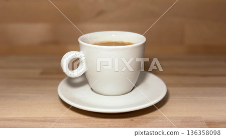 White coffee cup with Americano on a white saucer on a wooden table with copy space White coffee cup with Americano on a white saucer on a wooden table with copy space 136358098